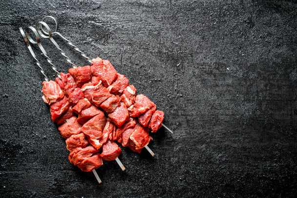 Brochetas de shish kebab crudo. Sobre fondo rústico negro
 - Foto, Imagen