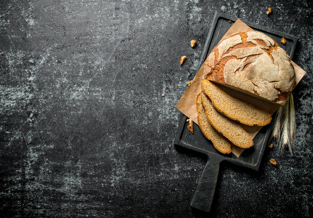 Sliced bread on a cutting Board. On black rustic background - 写真・画像