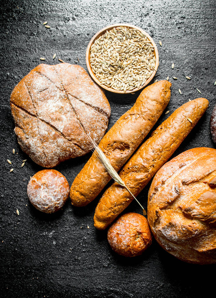 Different types of wheat and rye bread. On black rustic background - Foto, Imagen