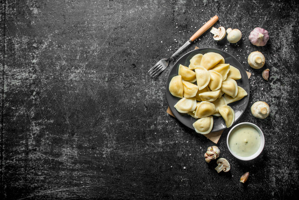 Dumplings with sour cream, garlic and mushrooms. On dark rustic background - 写真・画像