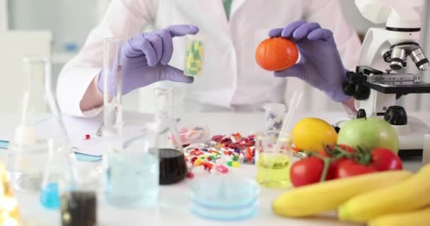 Bilim adamı laboratuarda ilaç ve portakal tutuyor. Yiyecek laboratuarında temel vitaminler. - Video, Çekim