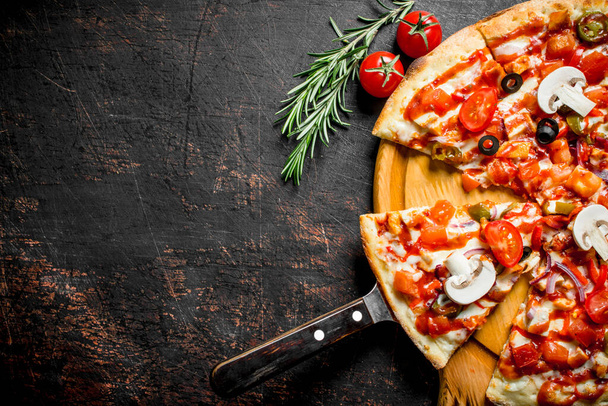 Sliced fragrant Mexican pizza on a cutting Board. On dark rustic background - Valokuva, kuva