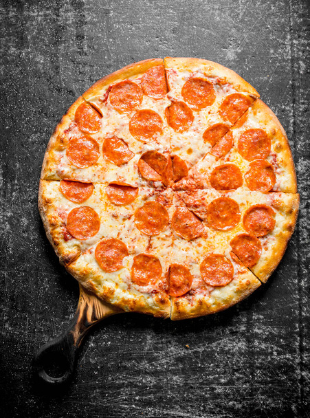 Fragrant pepperoni pizza on the cutting Board. On dark rustic background - Foto, Bild