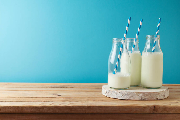 Jewish holiday Shavuot concept with milk bottles on wooden table over blue background - Foto, Imagem