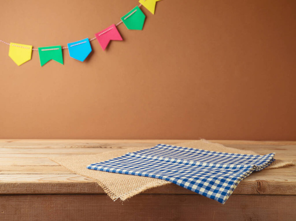 Brazilian Festa Junina summer harvest festival concept. Empty wooden table with tablecloth over wall  background. Mock up for design and product display - Photo, Image