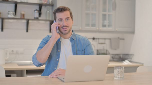 Fiatalember beszél telefonon a munkahelyen - Fotó, kép