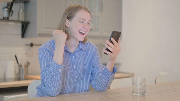 Νεαρή γυναίκα γιορτάζει on-line Κερδίστε στο τηλέφωνο - Φωτογραφία, εικόνα