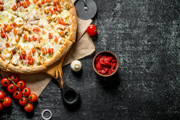Hot pizza on paper with cherry tomatoes. On dark rustic background - Fotó, kép