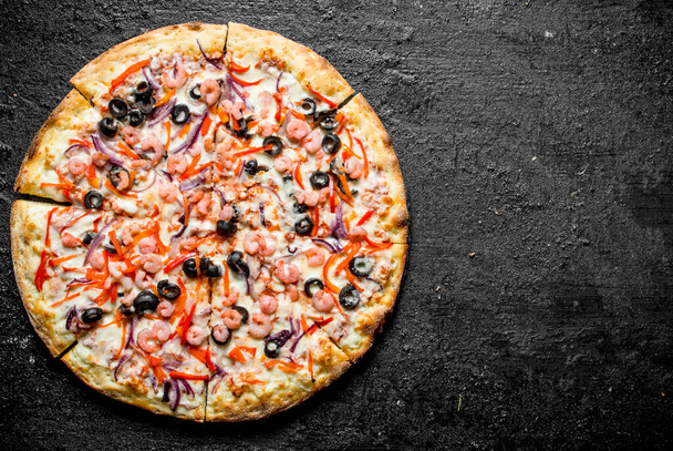 Pizza with shrimp, olives and red onions. On black rustic background - Foto, imagen
