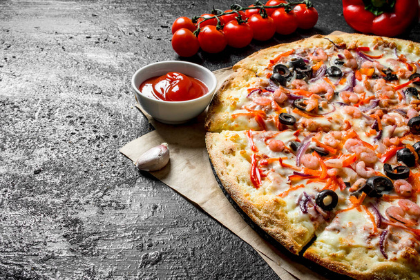 Illatos tengeri pizza garnéla és olajbogyó. Fekete rusztikus háttér - Fotó, kép