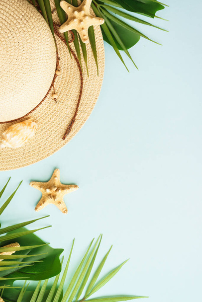 Summer flat lay background. Summer vacation and travel concept. Palm leaves, sea shells and hat on blue background. Vertical. - Photo, Image