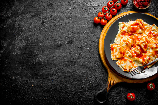Ravioli z pomidorami wiśniowym i sosem. Na czarnym tle rustykalnym - Zdjęcie, obraz