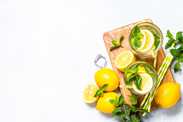 Lemonade in glass with fresh lemons and mint. Cold summer drink top view with copy space. - Foto, Imagen