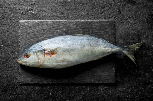 Raw fish on a stone Board. On black rustic background - Fotó, kép