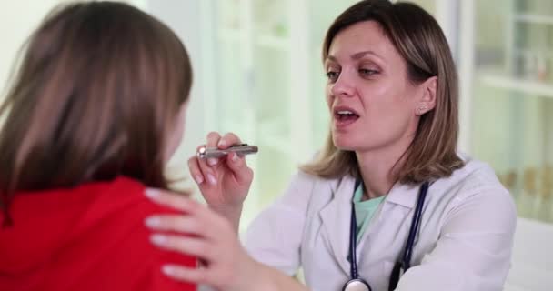 Otorhinolaryngologist обстежує дівчинку болючим горлом. Фарінгіт у дітей викликає симптоми і лікування. - Кадри, відео