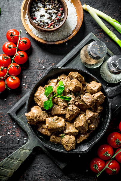 Fried liver with spices and cherry tomatoes on a cutting Board. On dark rustic background - Fotografie, Obrázek
