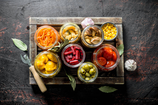 Various preserved vegetables on wooden tray. On dark rustic background - Foto, afbeelding