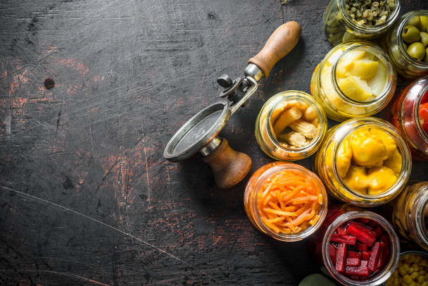 Pickled vegetables in glass jars. On dark rustic background - Fotó, kép
