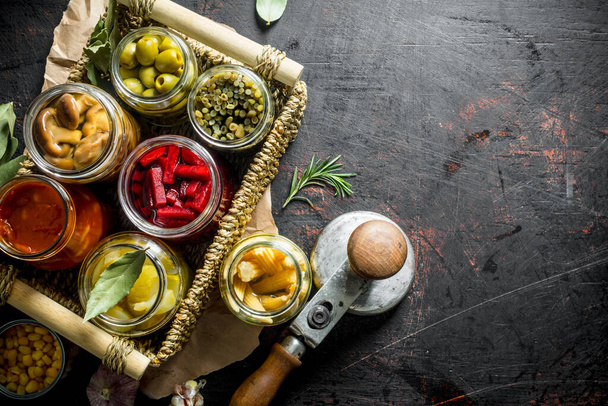 Homemade pickled vegetables in jars on the tray. On dark rustic background - Photo, Image