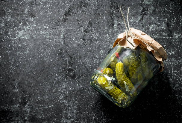 Pickles in a glass jar. On dark rustic background - Фото, изображение