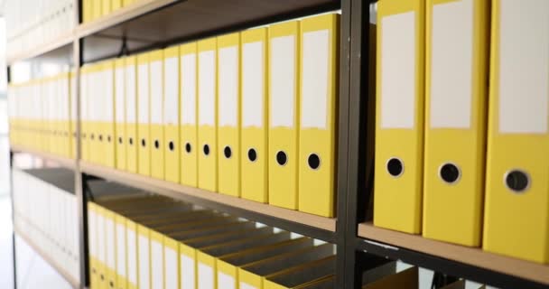 同じ黄色のオフィスフォルダでいっぱいの棚。ドキュメントのアーカイブとビジネス文書の保存 - 映像、動画