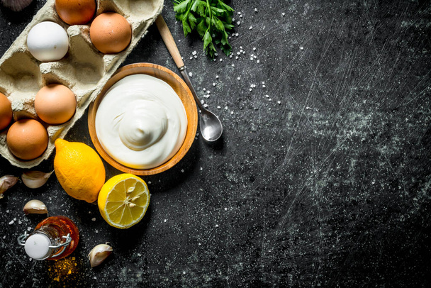 Mayonnaise with eggs and lemon. On dark rustic background - 写真・画像