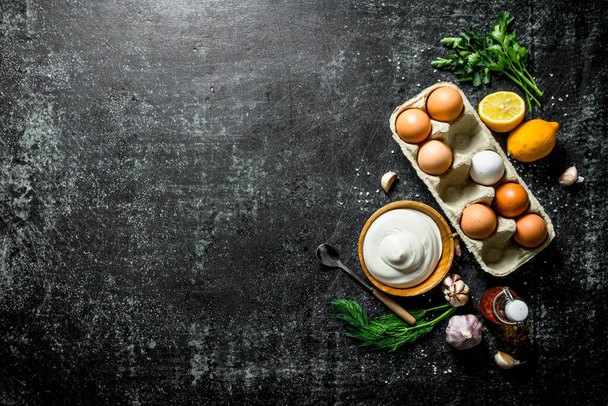 Mayonnaise with eggs, herbs and garlic. On dark rustic background - 写真・画像