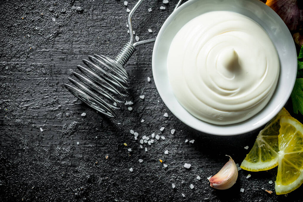 Mayonnaise with lemon and garlic. On black rustic background - 写真・画像