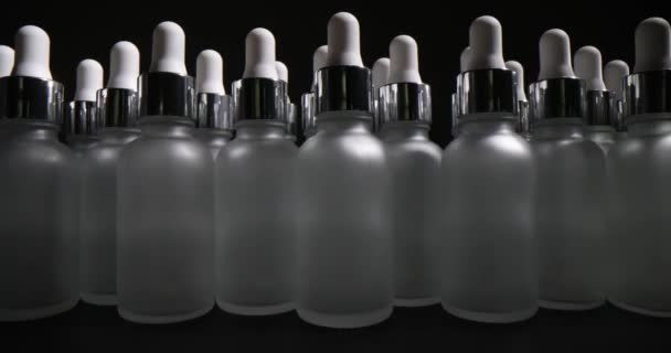 Glazen fles met druppelaar op grijze achtergrond. Productie van cosmetische verpakkingen - Video