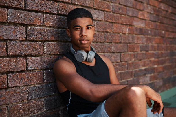 I have the determination to go for all my goals. Portrait of a sporty young man sitting against a wall outdoors - Foto, imagen