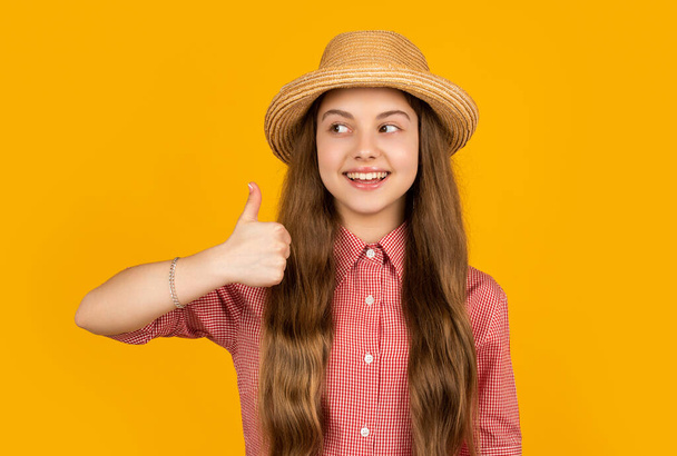 happy teen girl in straw hat on yellow background. thumb up. - Zdjęcie, obraz