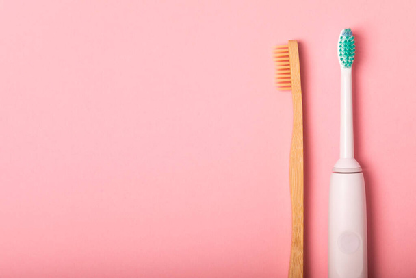 electric toothbrush, bamboo and handmade toothbrushes on a pink background with copy space. Flat lay. Oral hygiene. Oral care kit. Dentist concept. Place for text. Place to copy. - Foto, imagen