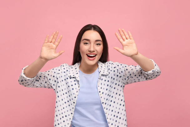 Happy woman giving high five with both hands on pink background - Φωτογραφία, εικόνα