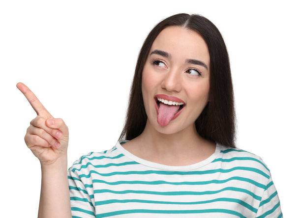 Happy woman showing her tongue and pointing at something on white background - Photo, image
