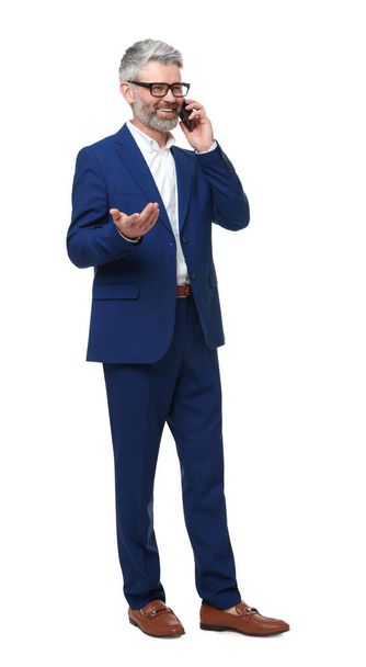Mature businessman in stylish clothes talking on smartphone against white background - Φωτογραφία, εικόνα