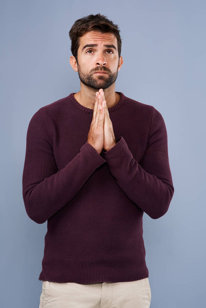 Praying for strength and guidance. Studio shot of a handsome young man praying against a gray background - Фото, изображение
