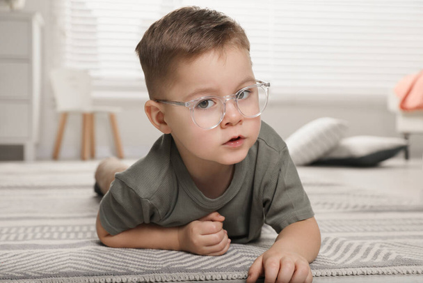 Cute little boy in glasses on floor at home - Foto, imagen