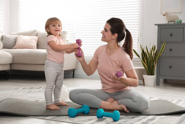 Mother and her daughter with dumbbells at home - 写真・画像