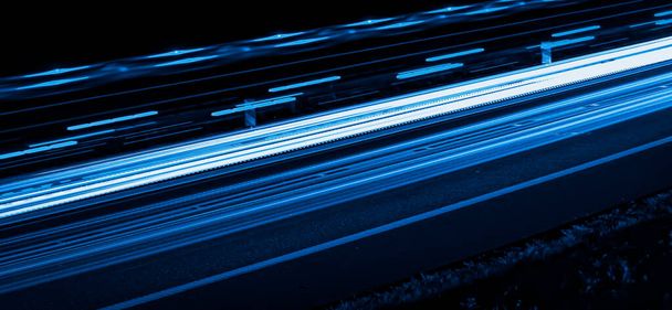 黒い背景の車のライトの青い線 - 写真・画像