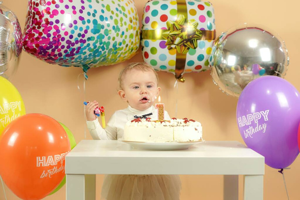 Surprised birthday girl on the background of balloons claps her hands. High quality photo - Foto, imagen