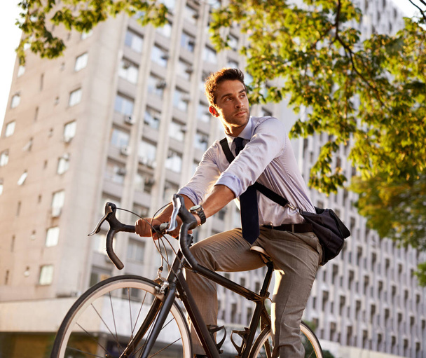 Cycling, bicycle and business man in city for commute, carbon neutral and transportation. Sustainable, professional and travel with male employee riding on bike in urban town for journey and trip. - Photo, Image