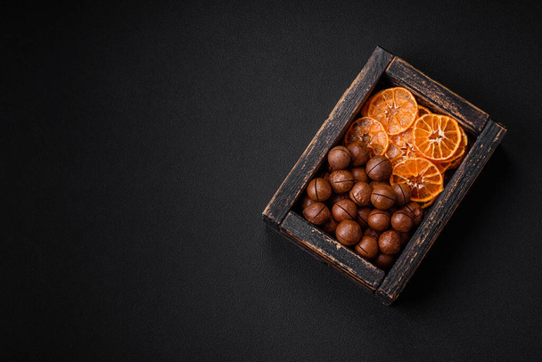 Köstliche geröstete Macadamia-Nüsse in der Schale vor dunklem Betonhintergrund. Vegetarisches Essen - Foto, Bild