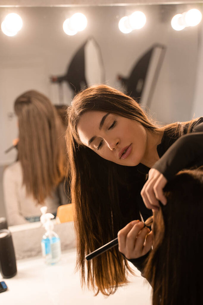 Vertical view of the makeup artist applies natural makeup to the face of the model. Cropped view of the visage process in studio. Stock photo - Φωτογραφία, εικόνα