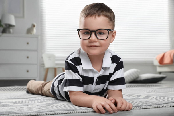 Cute little boy in glasses on floor at home - 写真・画像