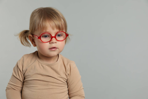 Cute little girl in glasses on light grey background. Space for text - Foto, Imagen