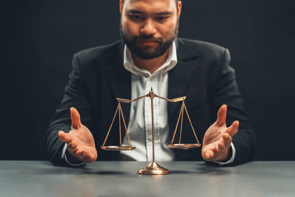 Focus golden scale balance with burred background of lawyer in black suit sit on his office desk, symbol of legal justice and integrity, balanced and ethical decision in court of law equility - Photo, Image