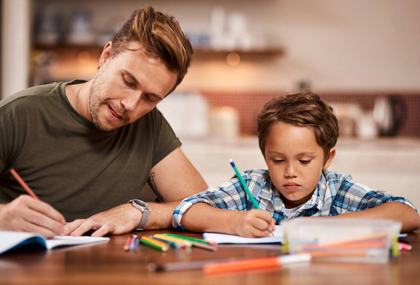 У нас обох є домашнє завдання. чоловік сидить зі своїм сином, поки він робить домашнє завдання
 - Фото, зображення
