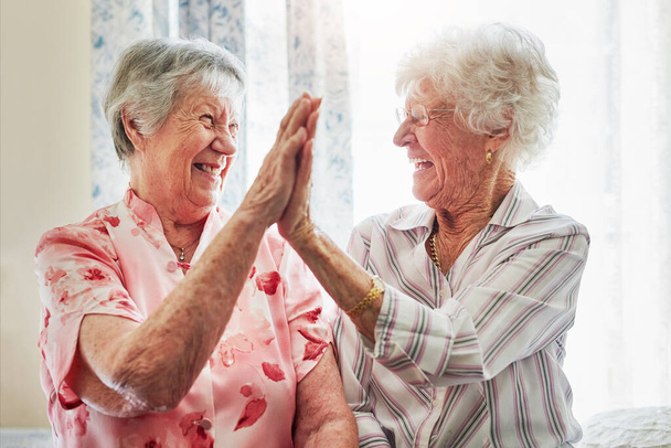 Happy, love en senior vrouwen met een high five voor zorg, pensioen en geluk. Glimlach, team en bejaarde vrienden met opgewonden gebaar voor solidariteit of levensstijl in een verpleeghuis samen. - Foto, afbeelding