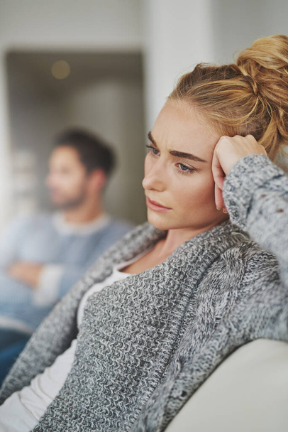 Sad, depression and woman in conflict with her boyfriend in the living room of their apartment. Upset, disappointed and moody female person in argument, fight or breakup with partner at their home - Fotó, kép
