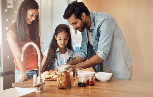 Transmitiendo su amor por la cocina. una familia joven y feliz preparando una comida en la cocina juntos en casa - Foto, imagen